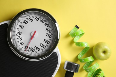 Photo of Bathroom scale, measuring tape, dumbbells and fresh apple on yellow background, flat lay