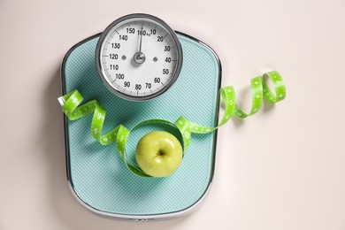 Photo of Scale, measuring tape and fresh apple on beige background, top view