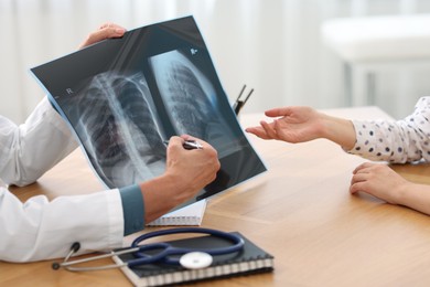 Photo of Lung disease. Doctor showing chest x-ray to her patient in clinic, closeup