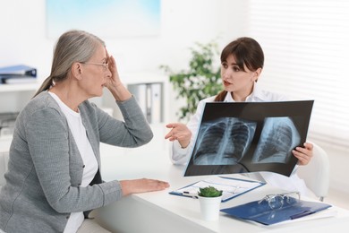 Photo of Lung disease. Doctor with chest x-ray consulting patient in clinic