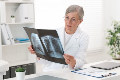 Photo of Lung disease. Doctor examining chest x-ray at table in clinic