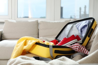 Open suitcase with traveler's belongings on bed, closeup