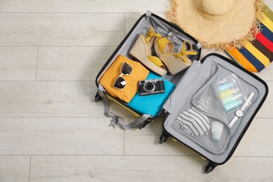 Photo of Open suitcase with traveler's belongings on floor, flat lay. Space for text