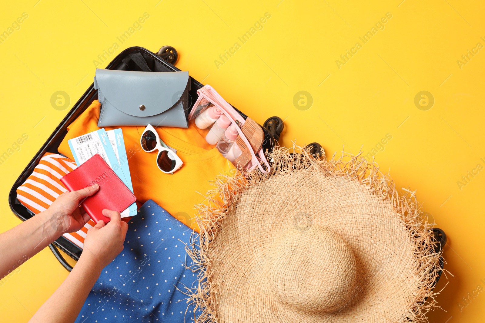 Photo of Woman packing suitcase on yellow background, top view. Space for text