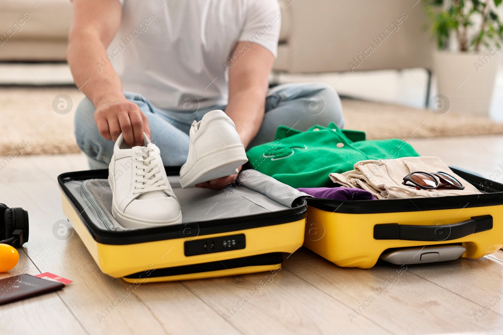 Photo of Man packing suitcase on floor at home, closeup