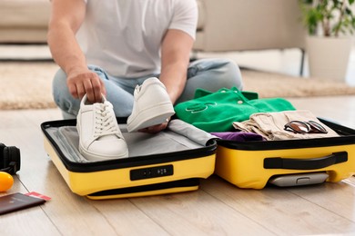 Photo of Man packing suitcase on floor at home, closeup