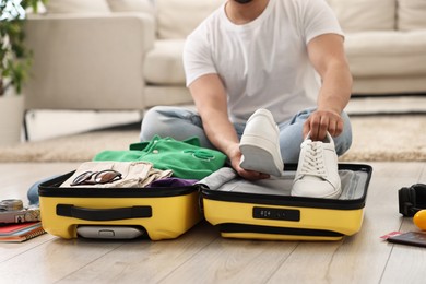 Photo of Man packing suitcase on floor at home, closeup