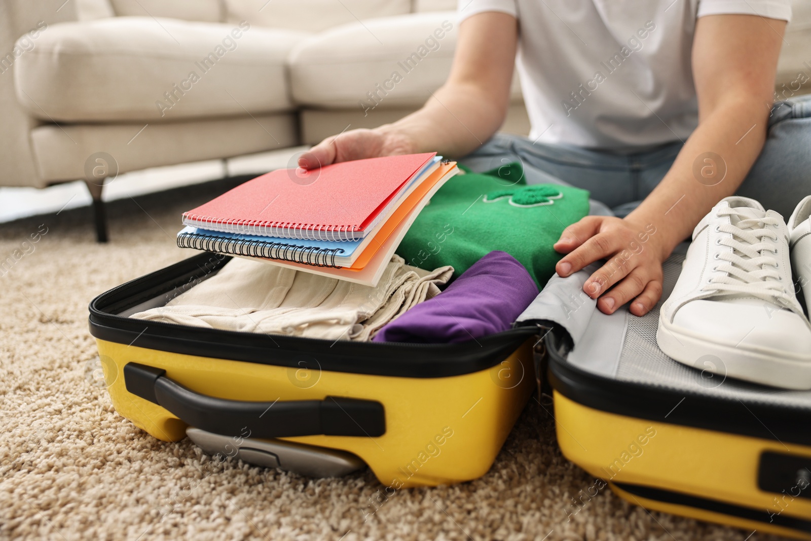 Photo of Man packing suitcase on floor at home, closeup