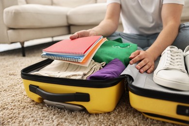 Photo of Man packing suitcase on floor at home, closeup