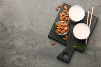 Photo of Glasses of almond milk and almonds on grey table, top view. Space for text