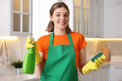 Photo of Cleaning service worker holding detergent and sponge in kitchen