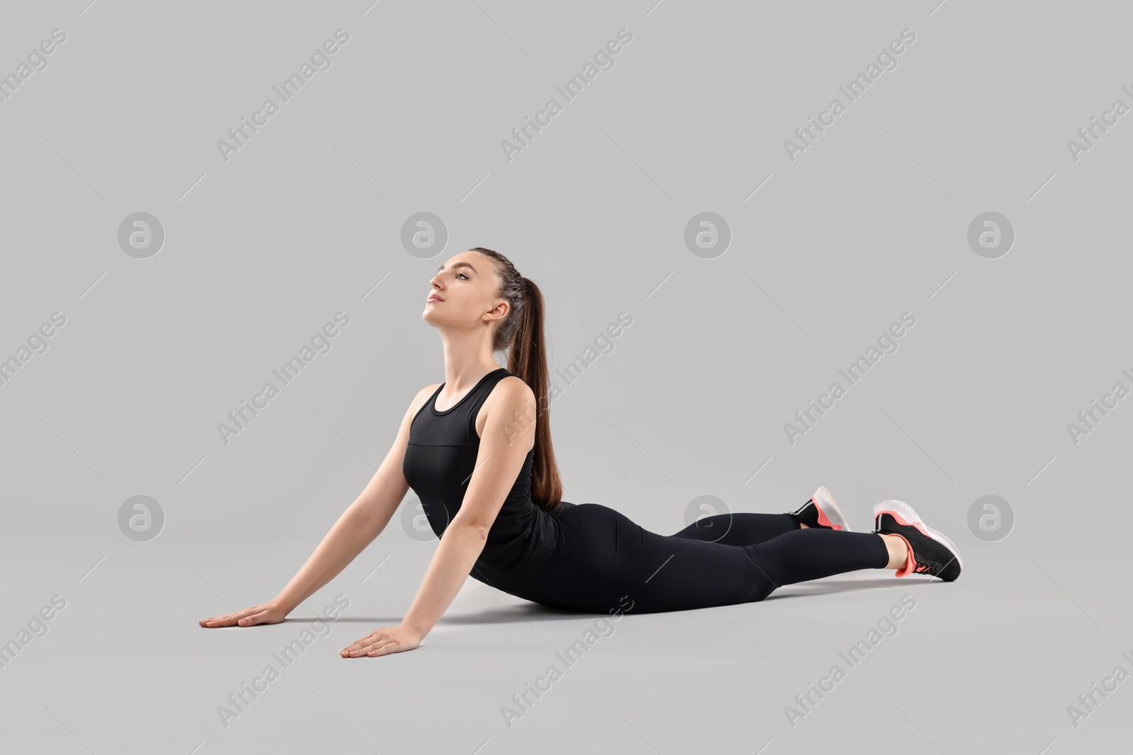 Photo of Aerobics. Young woman doing stretching exercise on light background