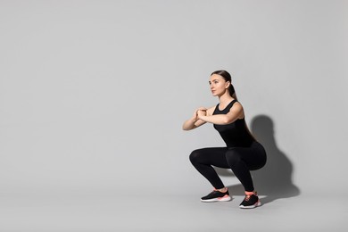 Photo of Young woman doing aerobic exercise on light grey background. Space for text