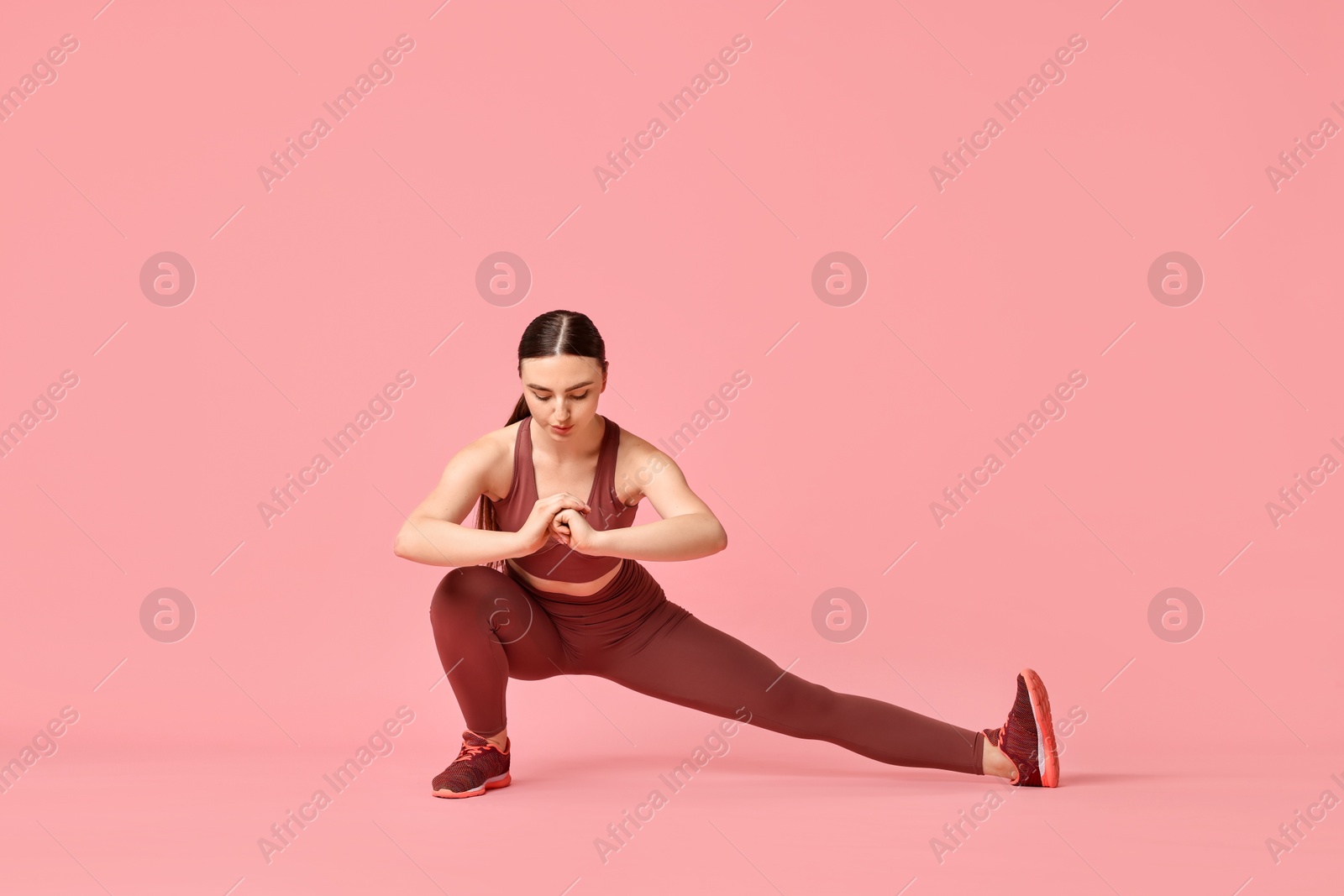 Photo of Aerobics. Young woman doing stretching exercise on pink background