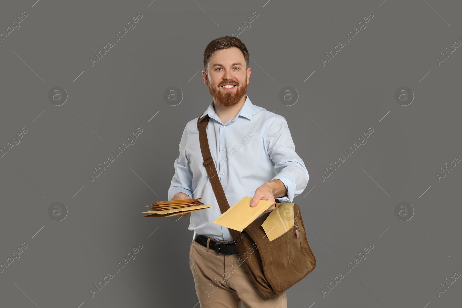 Photo of Postman with brown bag delivering letters on grey background