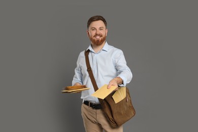 Photo of Postman with brown bag delivering letters on grey background