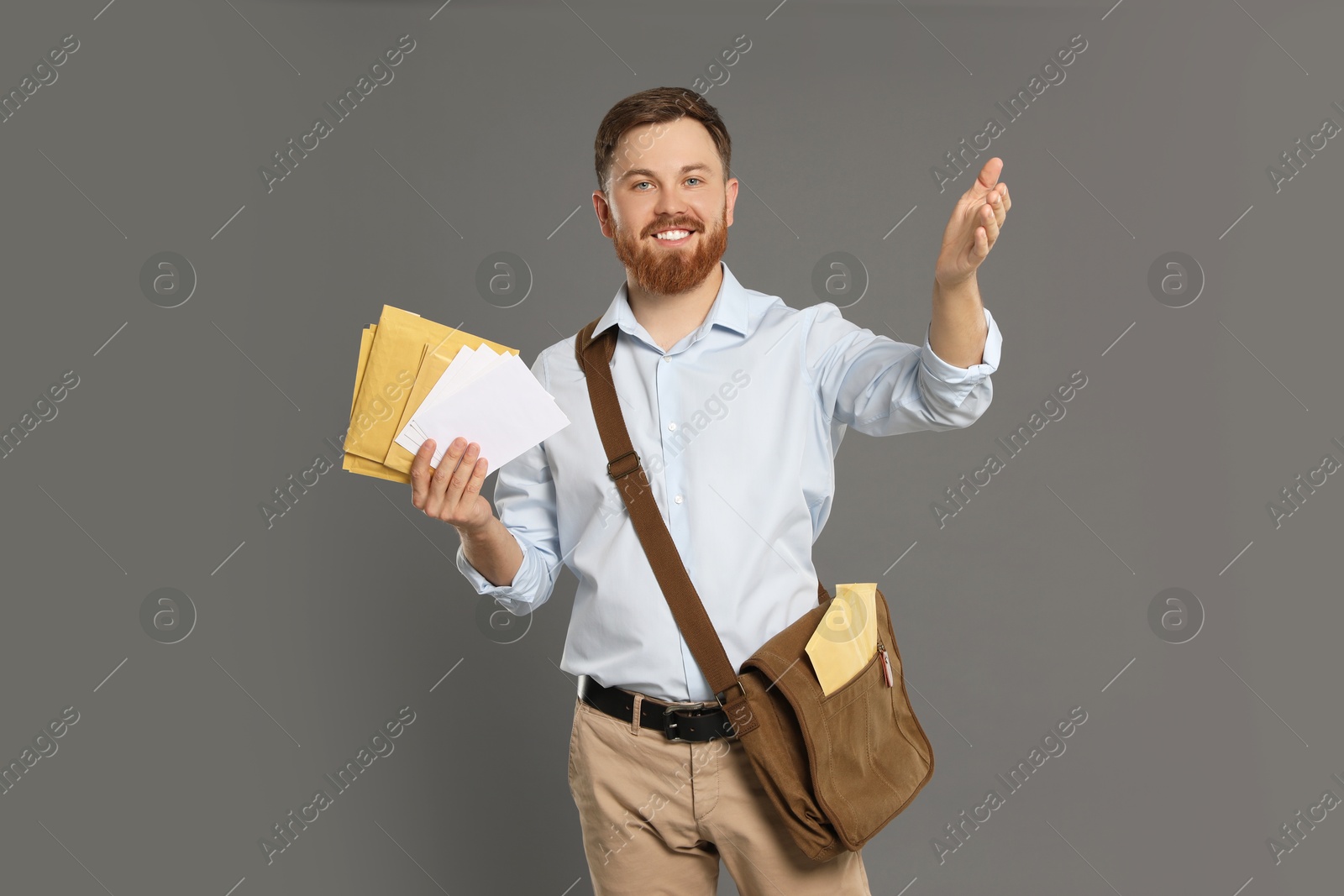 Photo of Postman with brown bag delivering letters on grey background