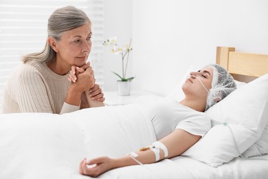 Photo of Coma patient. Sad mature woman near her unconscious daughter in hospital