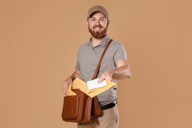 Happy young postman with leather bag delivering letters on brown background