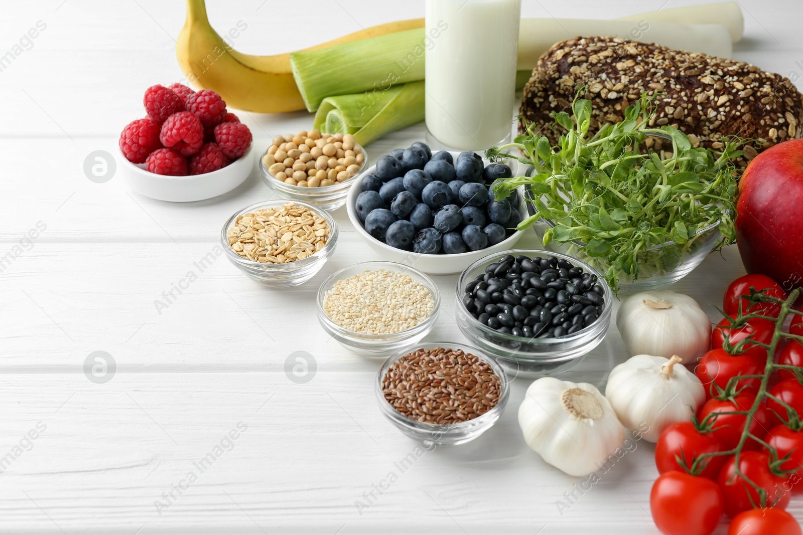 Photo of Different fresh products on white wooden table, space for text. Source of prebiotics