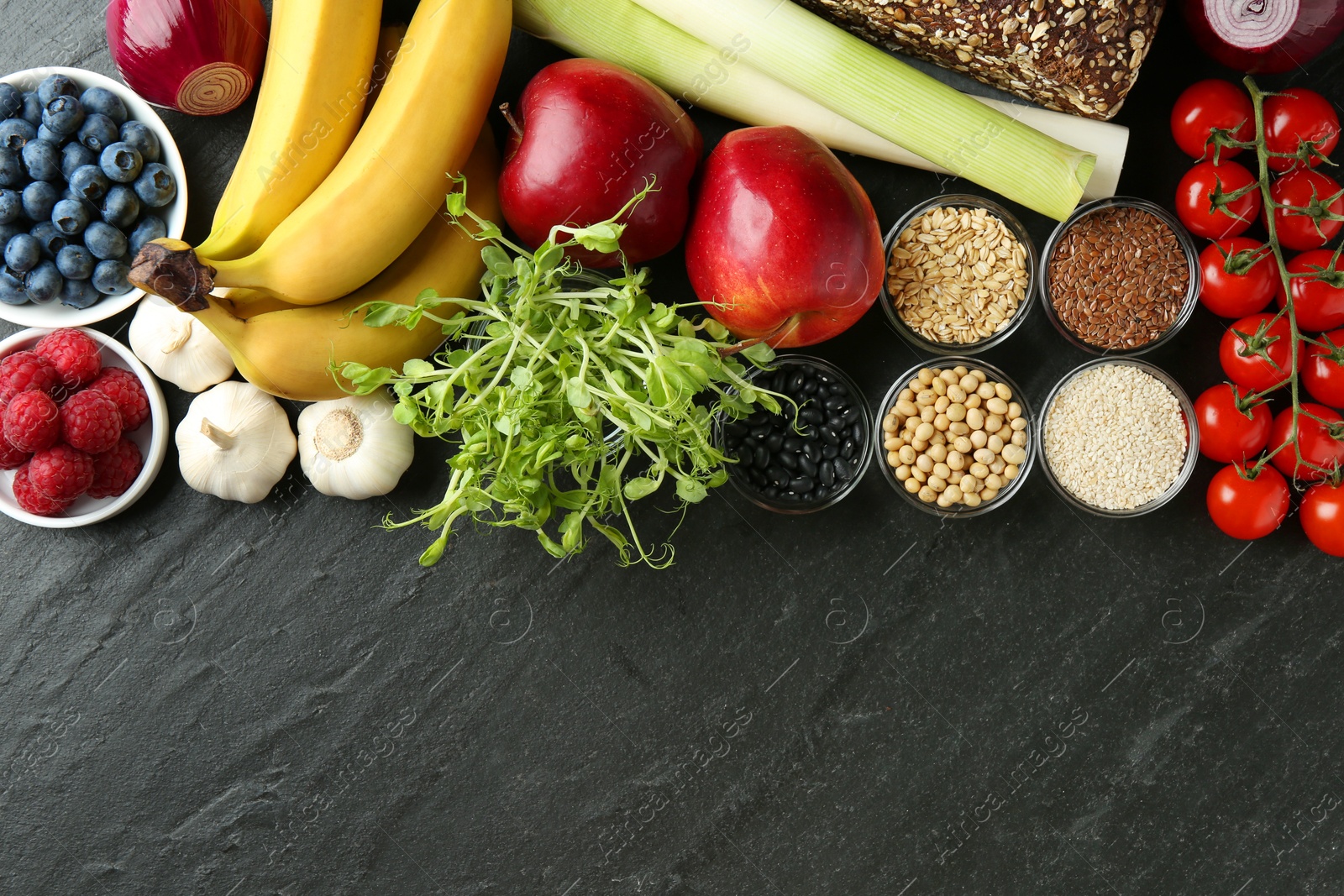 Photo of Different fresh products and space for text on black table, flat lay. Source of prebiotics