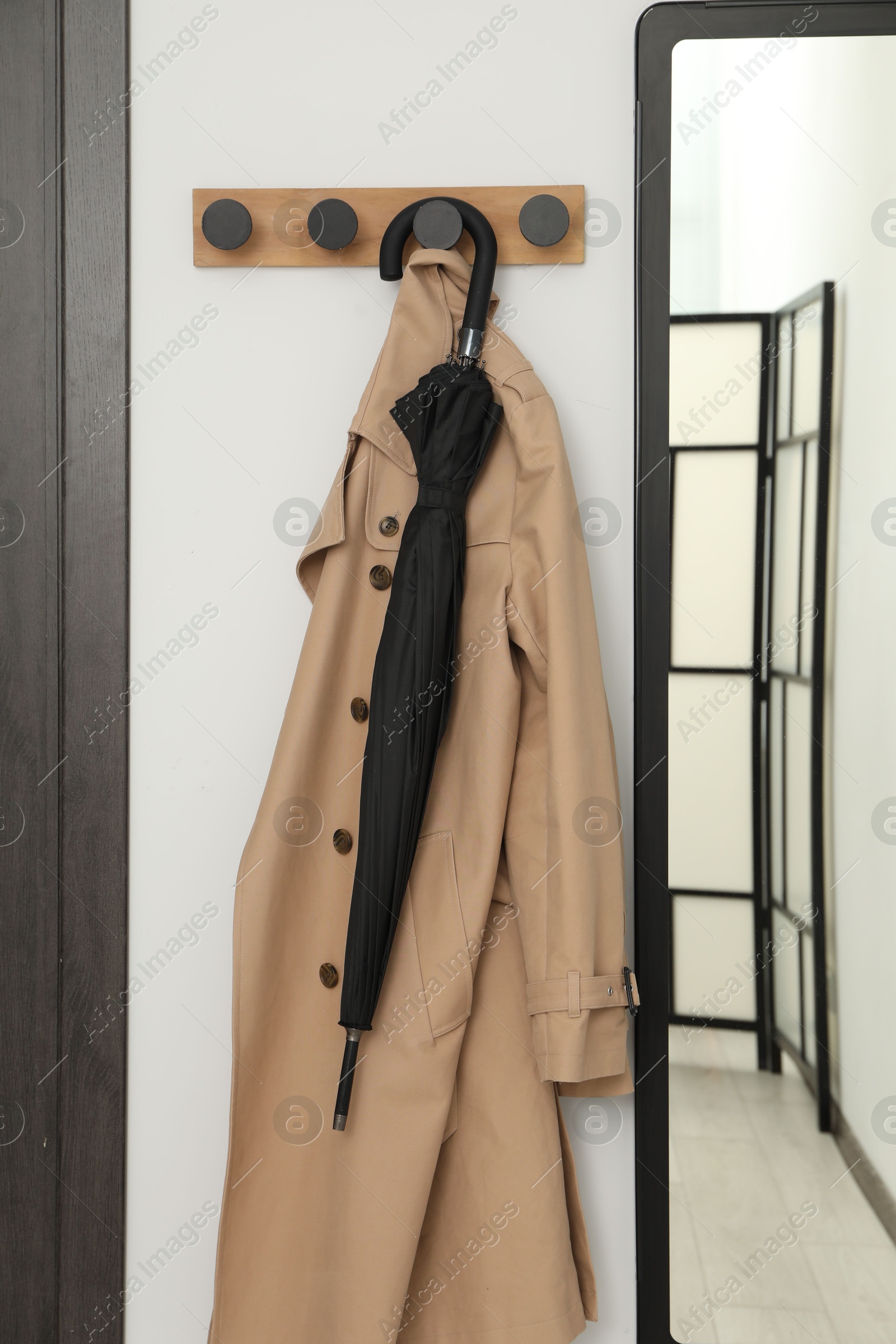 Photo of Black umbrella, coat, rack and mirror in hallway