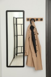 Black umbrella, coat, rack and mirror in hallway