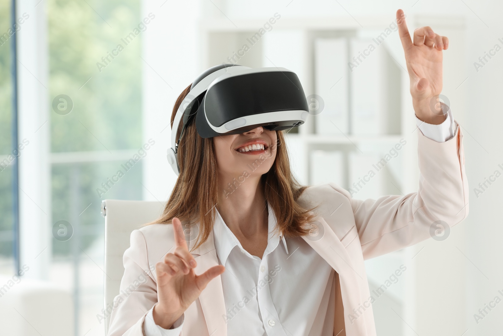 Photo of Smiling woman using virtual reality headset in office