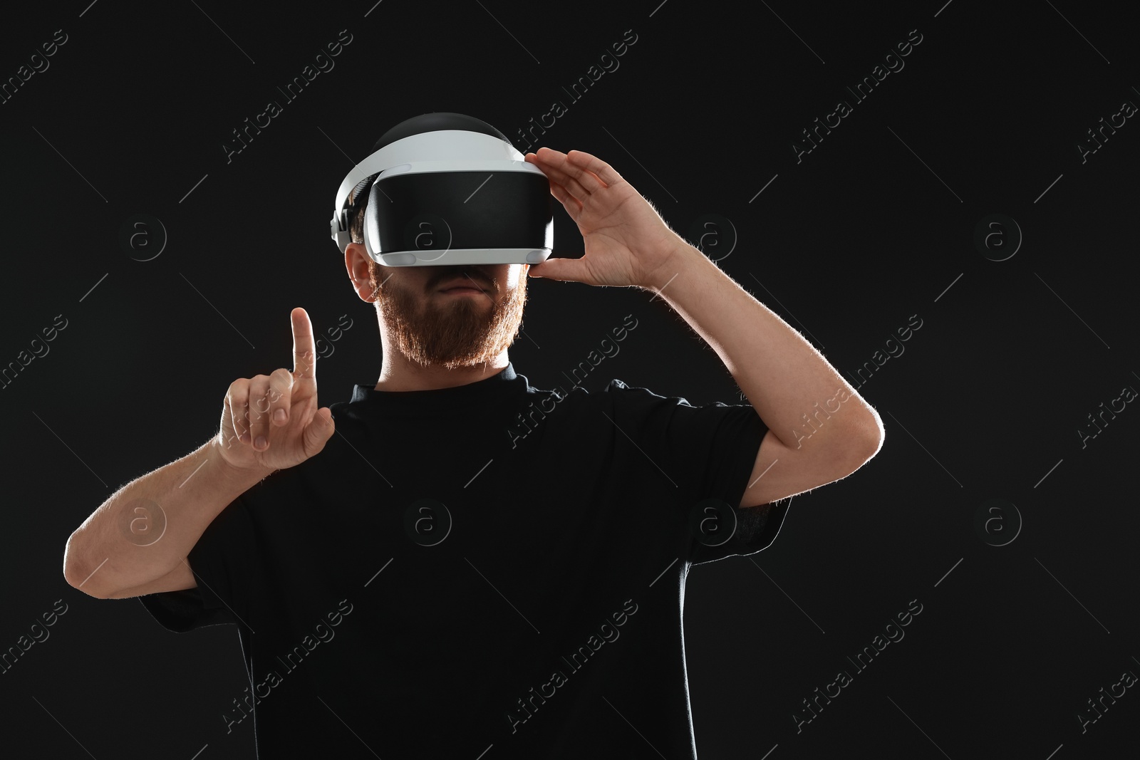 Photo of Man using virtual reality headset on black background