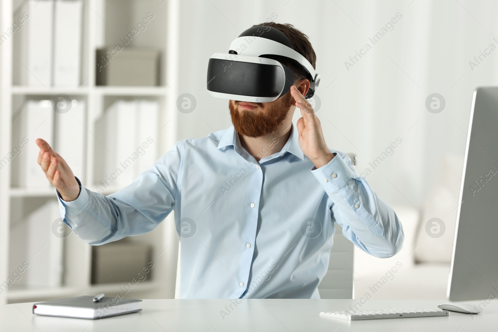 Photo of Man using virtual reality headset at workplace in office