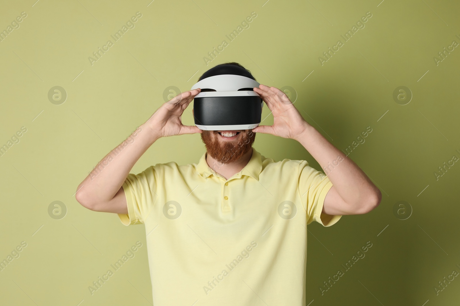 Photo of Smiling man using virtual reality headset on pale green background