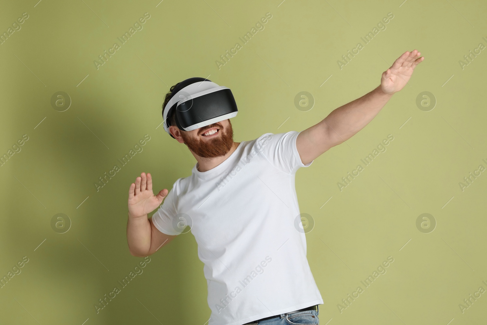 Photo of Smiling man using virtual reality headset on pale green background