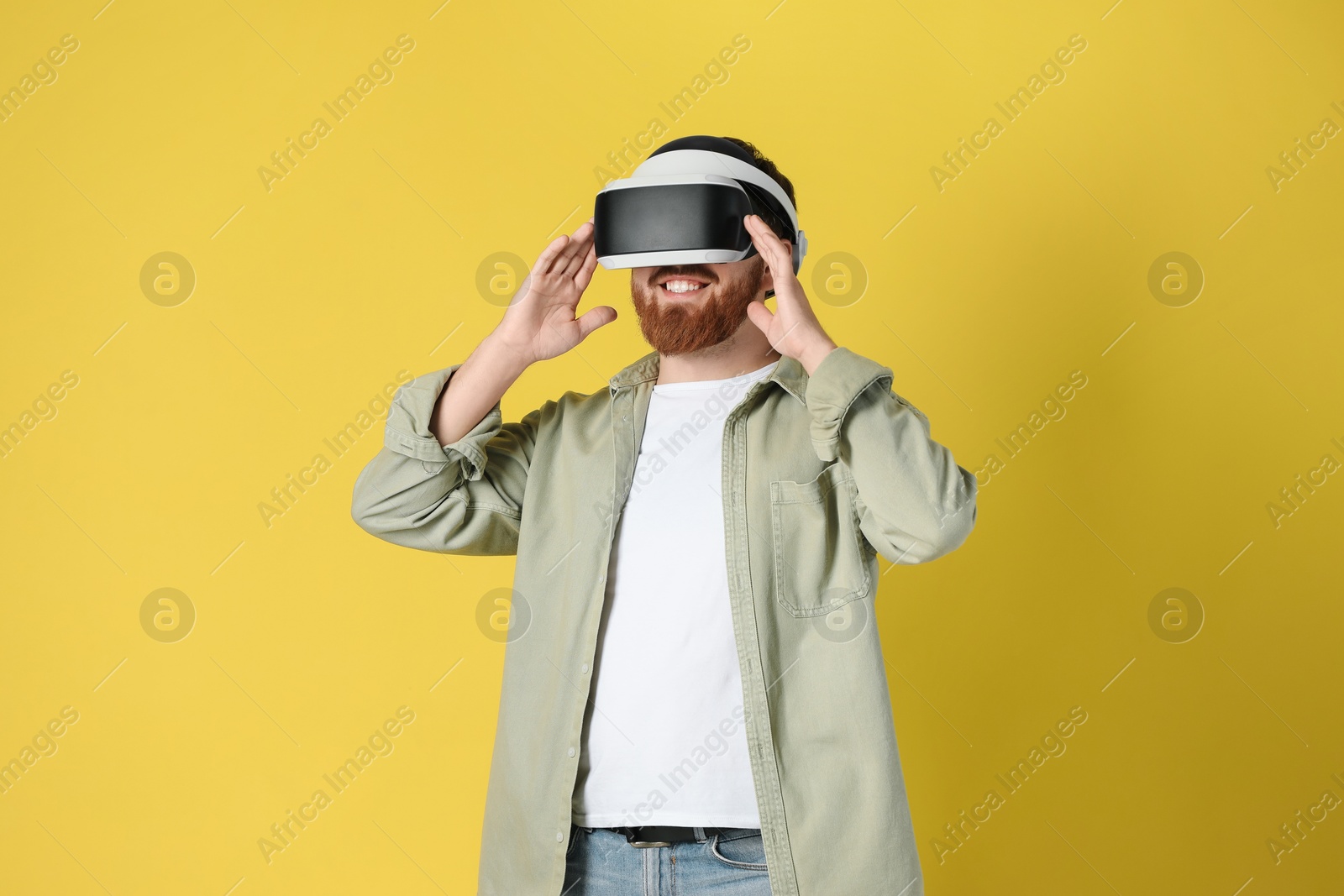 Photo of Happy man using virtual reality headset on pale yellow background