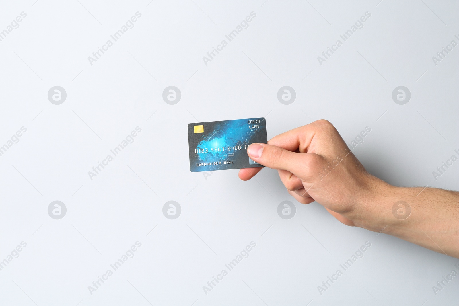 Photo of Man holding credit card on light grey background, closeup