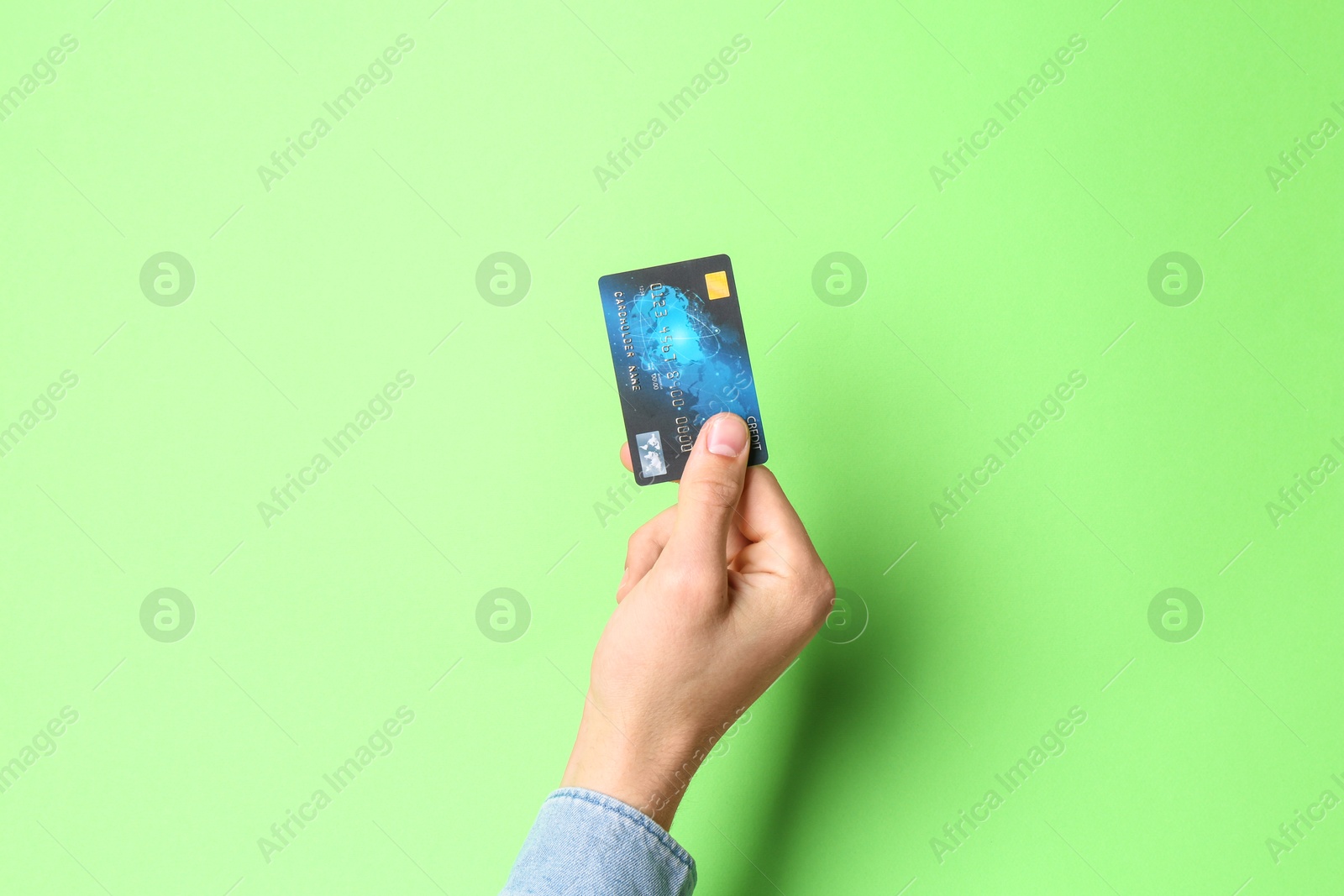 Photo of Man holding credit card on light green background, closeup