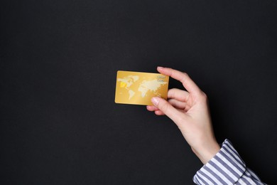 Woman holding credit card on black background, closeup