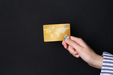 Photo of Woman holding credit card on black background, closeup