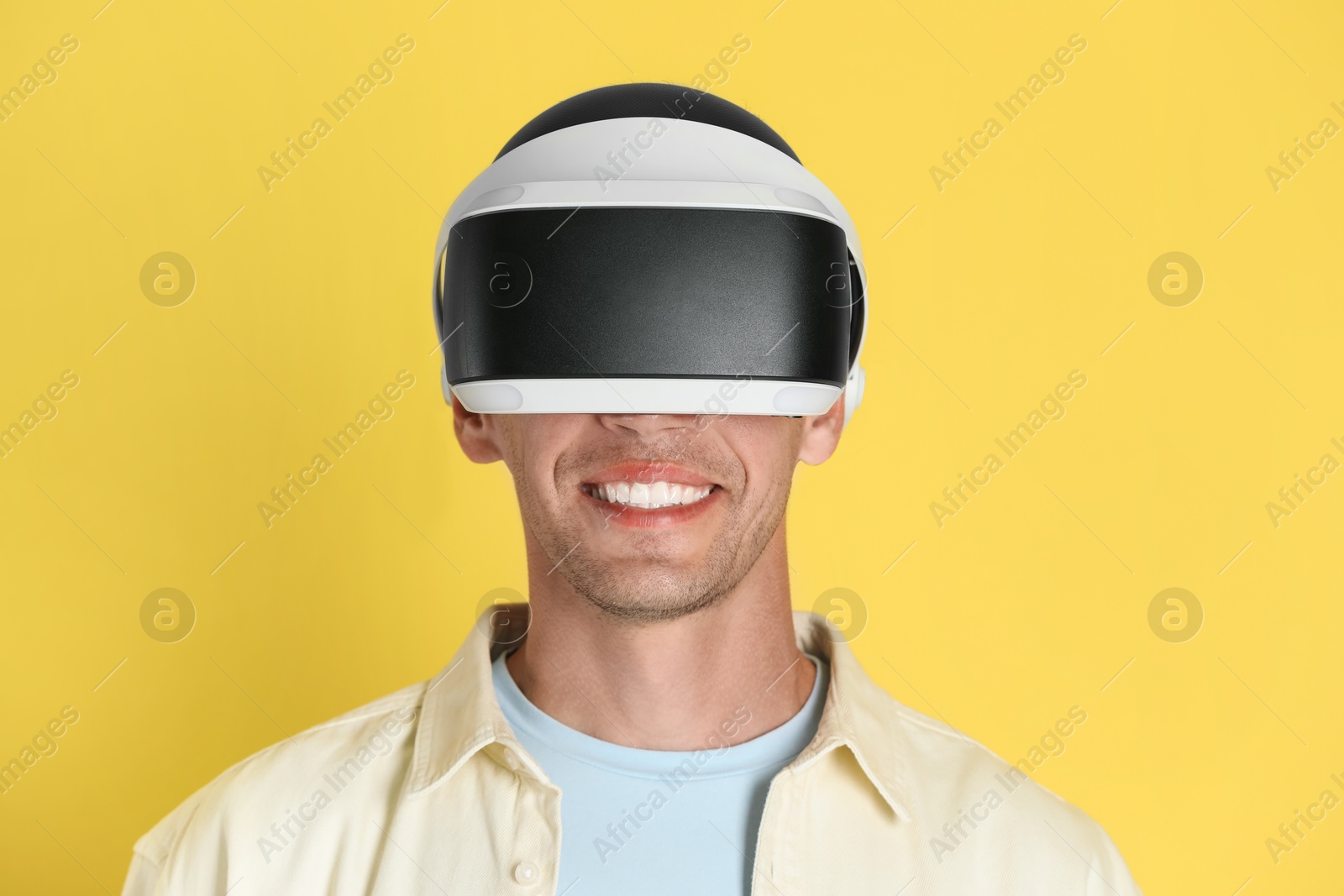 Photo of Smiling man using virtual reality headset on yellow background