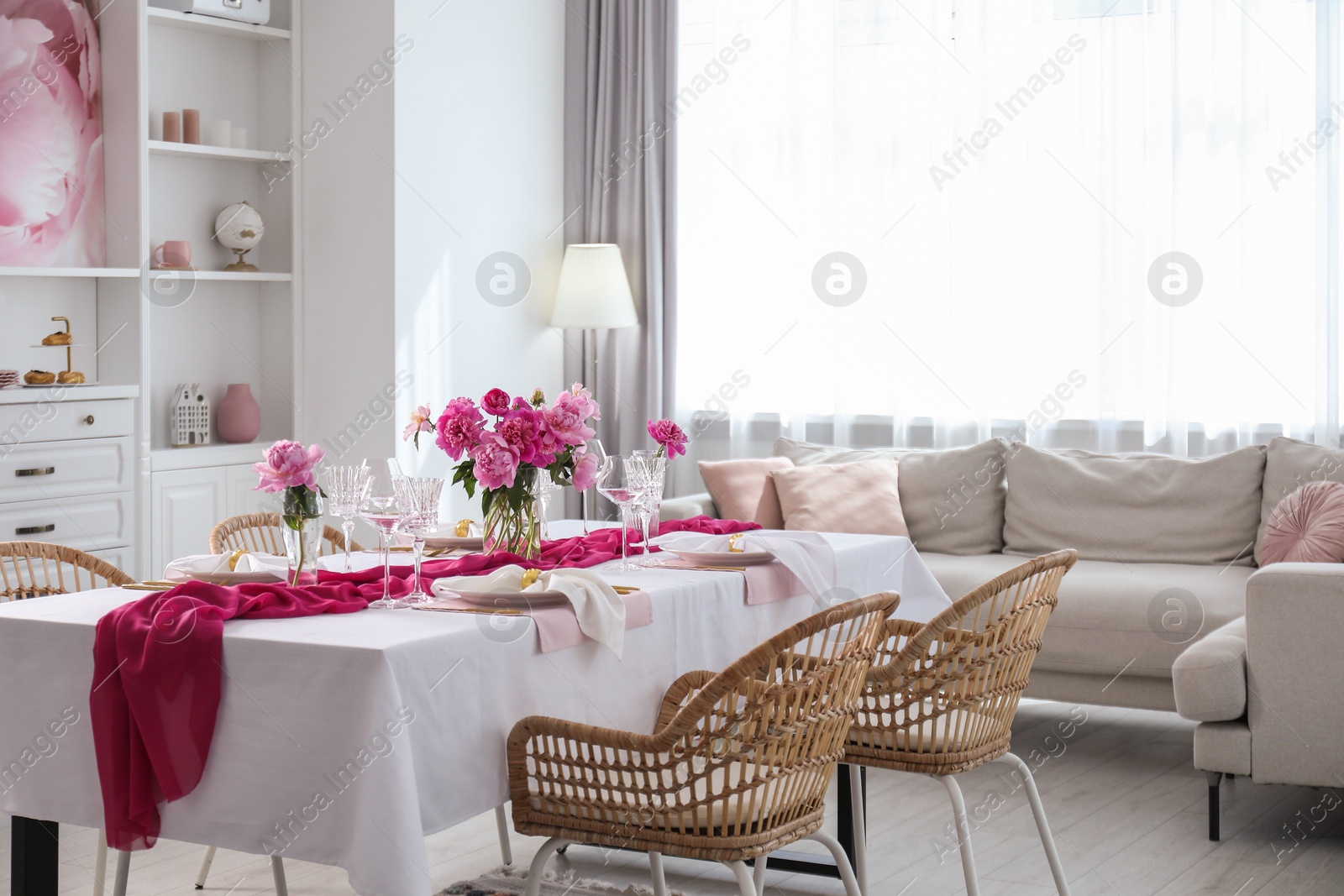 Photo of Beautiful table setting with flowers and rattan chairs in dining room