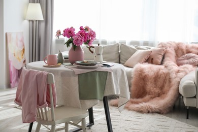 Photo of Beautiful table setting with pink peonies in living room