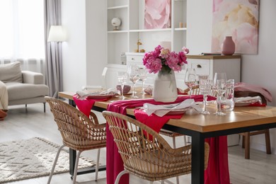 Photo of Pink peonies on table with beautiful setting and rattan chairs in dining room