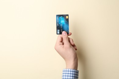 Man holding credit card on beige background, closeup