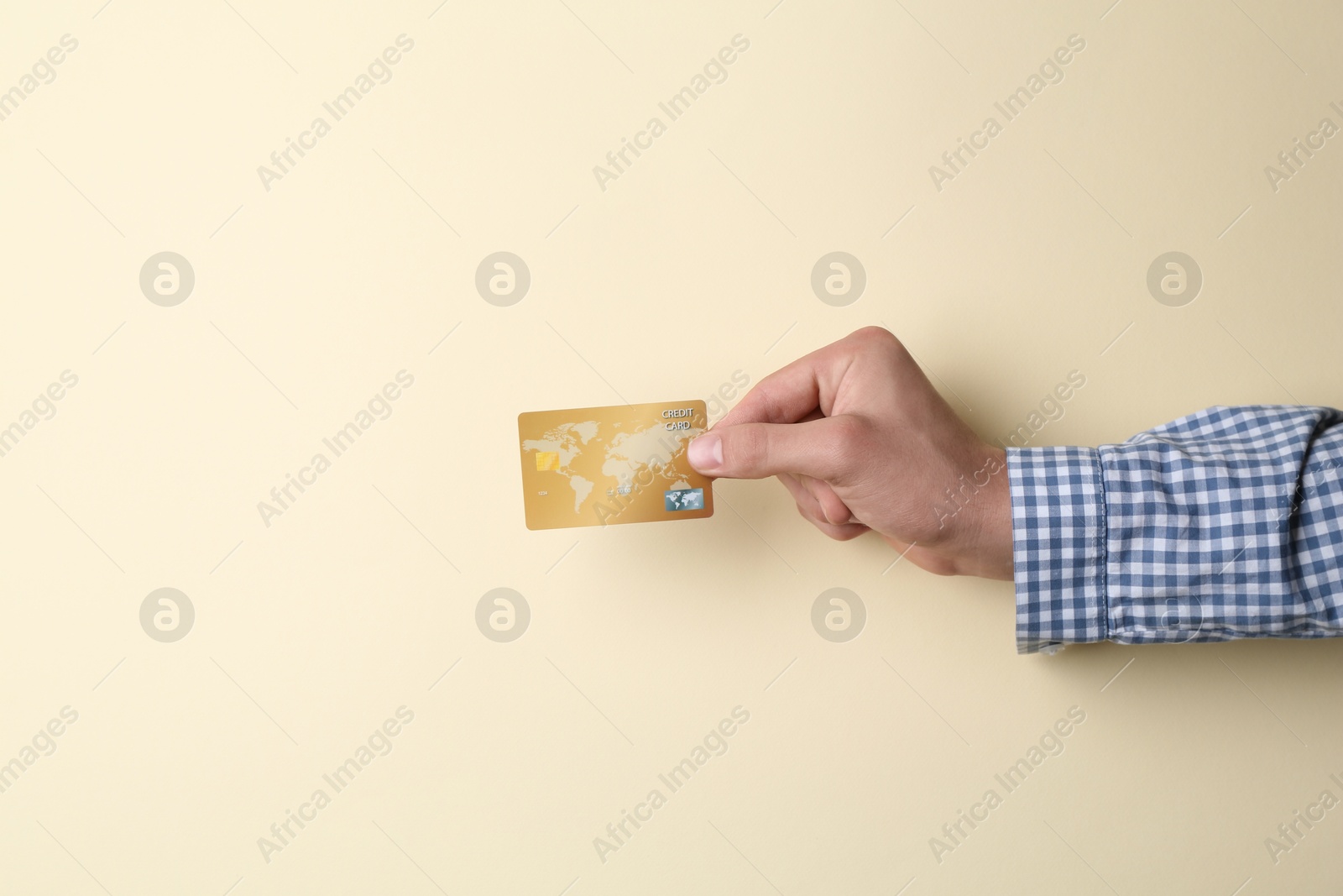 Photo of Man holding credit card on beige background, closeup