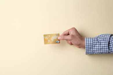 Man holding credit card on beige background, closeup