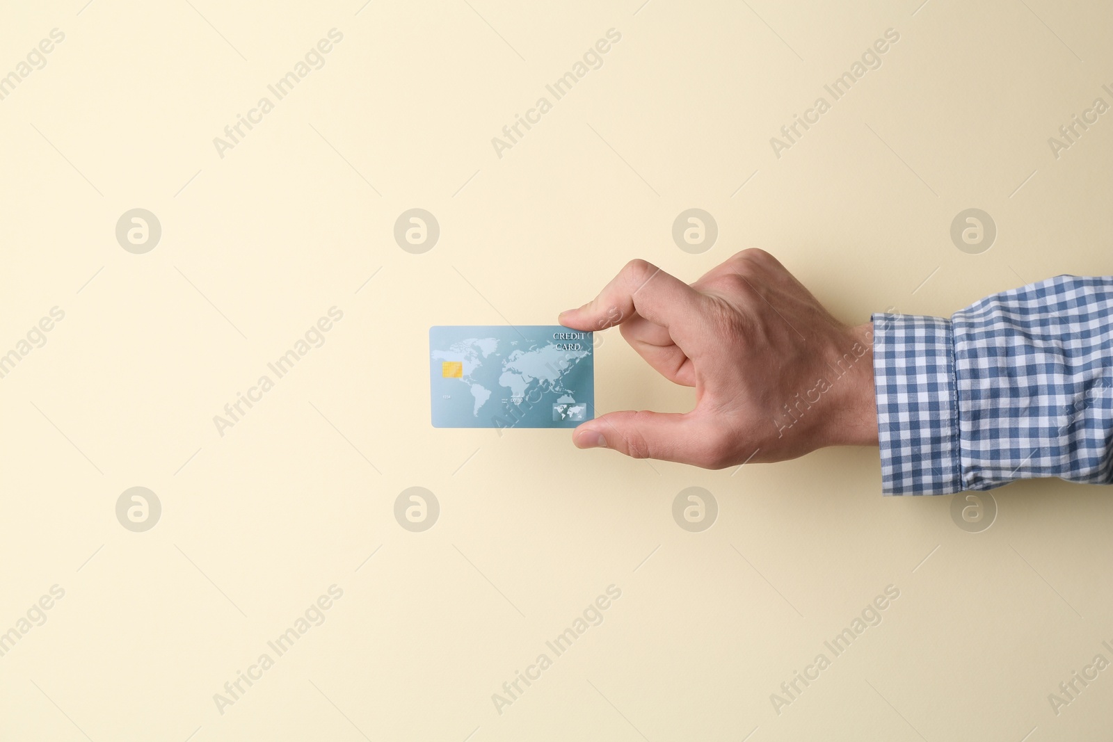 Photo of Man holding credit card on beige background, closeup