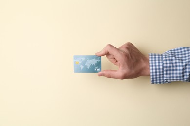 Photo of Man holding credit card on beige background, closeup