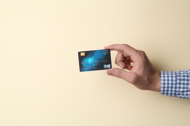 Man holding credit card on beige background, closeup