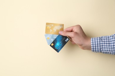 Man holding credit cards on beige background, closeup