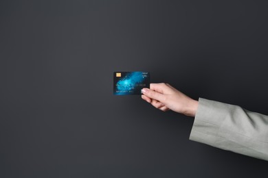 Woman holding credit card on black background, closeup