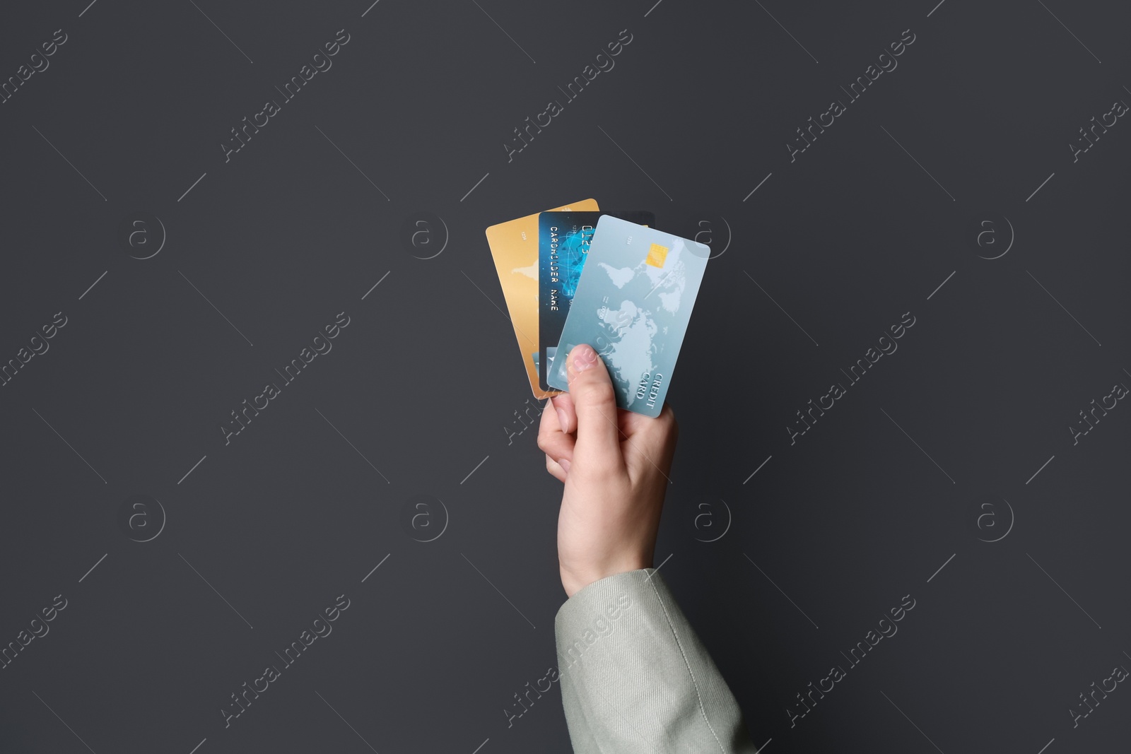 Photo of Woman holding credit cards on black background, closeup